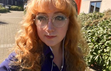 Falmouth University student wearing white headphones and a purple shirt