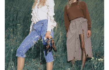 Two female fashion models in a field, wearing Jeans and a skirt