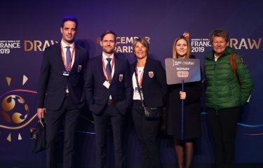 Five people standing in front of a purple wall with France 2019 FIFA