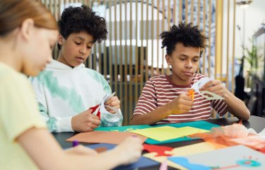 Young adults cutting out pieces of coloured paper