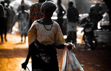 Woman in African dress carrying bags