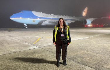 Sustainable Tourism Management wearing a high vis jacket, standing in front of a plane