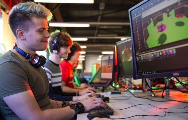 Games student smiling and working on artwork on a computer screen.