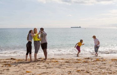 Five Falmouth University students on a sandy beach with the sea in the background