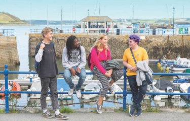 Falmouth University students sitting by the harbour on a sunny day