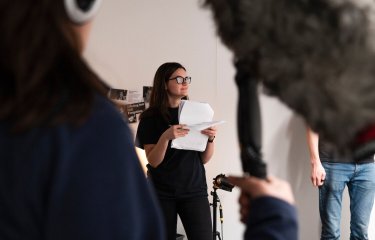 Film student standing holding pieces of paper