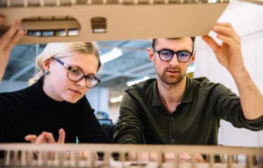 Interior design students looking inside a model.