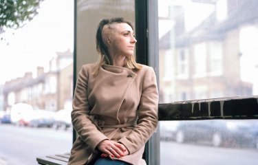 A woman with burns on her head sitting at a bus stop