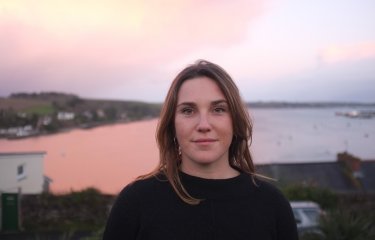 Head shot of graduate Jess Fairlie, with sea view in background