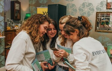 A group of Creative Event Management BA(Hons) students huddled round looking at a phone