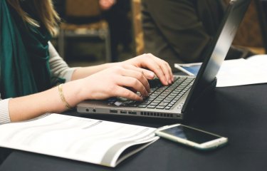 Woman studying at laptop with books and journals