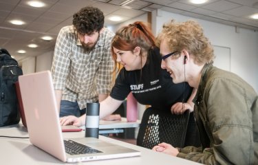 Three students around laptop