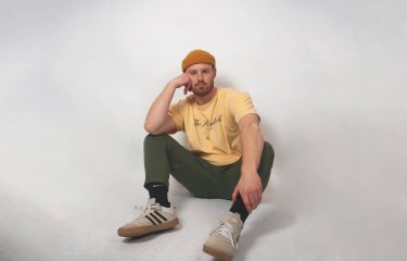 Sustainable Product Design student sitting on the floor wearing an orange hat and yellow tshirt