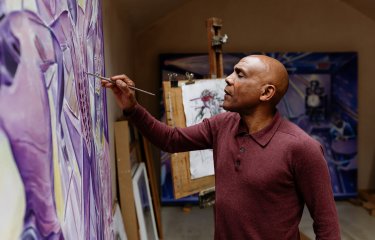 Denzil Forrester painting on a canvas in his studio
