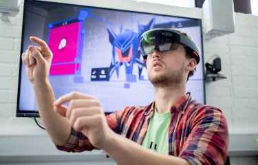 A Falmouth University student wearing a VR headset and a checked shirt