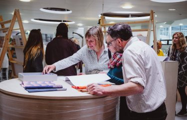 A girl with her parents looking through sketchbooks at a Falmouth University Open Day