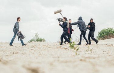 Students man cameras and lighting equipment on the set of Origin