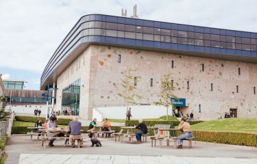 People and benches outside the Stannary buidling on Penryn campus.