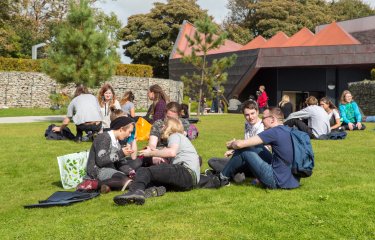 Lot's of students hanging out on the grass at Penryn campus.