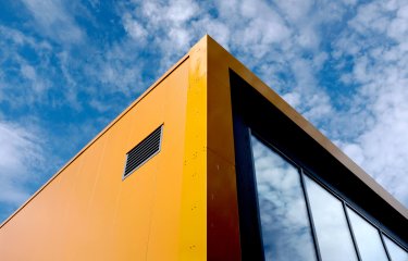 Orange and black Penryn Campus Sports Hall building with blue sky in the background