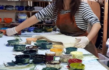 A girl in a studio surrounded by paint pots