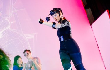 Female student wearing games development headset in front of a pink background