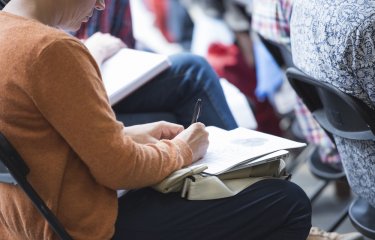 A woman seated writing in her notebook