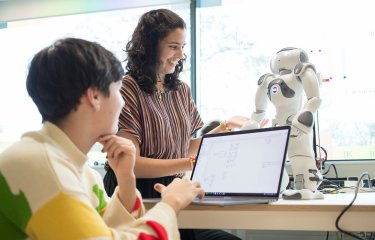 Two Robotics students operating a small robot with a laptop