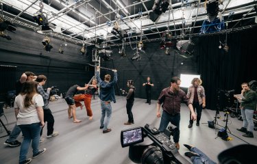 Film students combat fighting and filming in a studio.