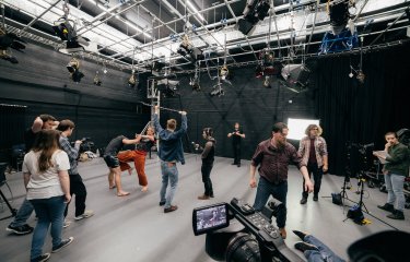 Film students combat fighting and filming in a studio.