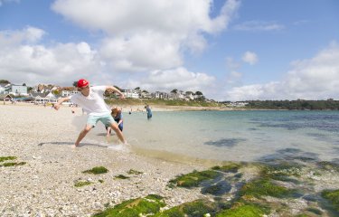 Falmouth University students throwing stones on the shore