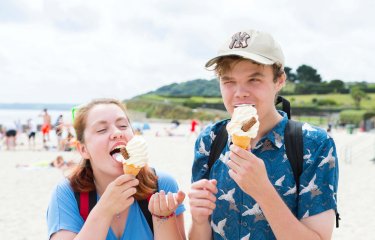 Two Falmouth University students eating ice creams on the beach