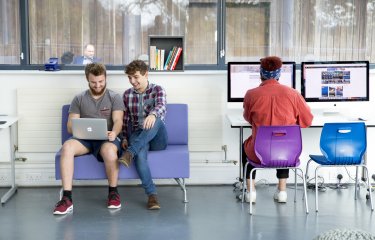 Business students looking at laptop together