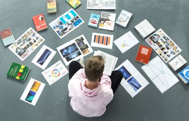 A Falmouth University student sat on the floor surrounded by papers and books