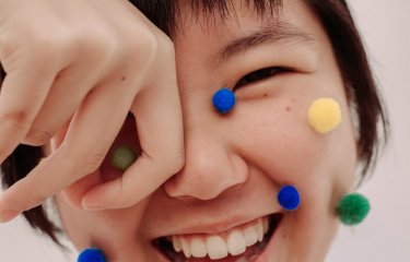 Smiling Asian girl with pompoms on her face