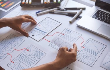 website layout plans on paper with hands and pens