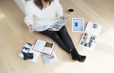 An online photography student sat on the floor with their work