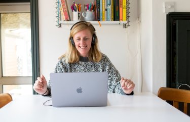 A woman smiling while looking at her laptop