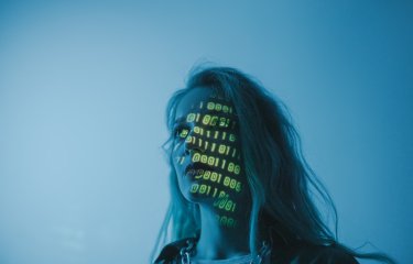 A woman in blue light with yellow numbers projected on her face