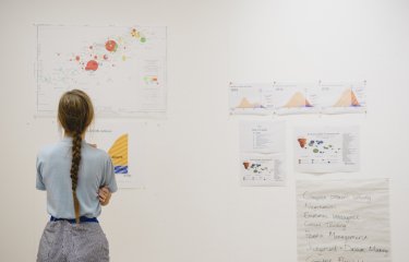 A girl looking at print outs of business graphs on a wall