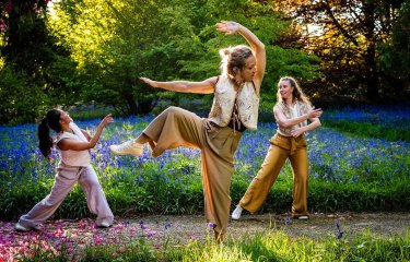 3 dancers performing outside in a woodland setting