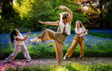 3 dancers performing outside in a woodland setting