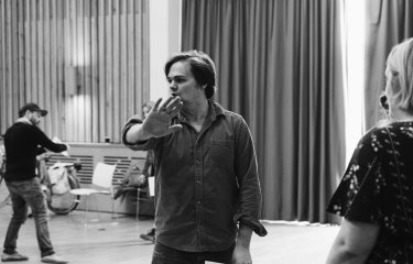 A male performer teaching a class looking away from the camera with his hand held out