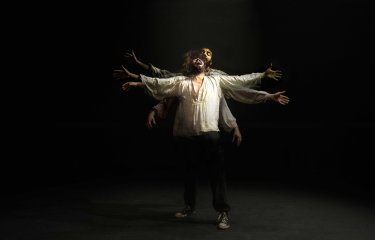 A person in the centre of the image with their arms spread out widely screaming