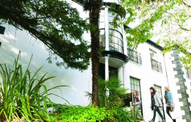 A white building behind greenery