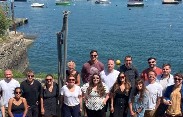 A large group of people standing in front of the sea and boats