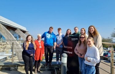 A group of Business & marketing students huddled together under blue sky during their micro-internship with Launchpad Venture Studio