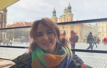 A young woman with red hair wearing a colourful scarf and coat