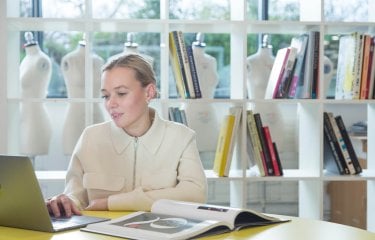Student working at laptop in front of bookcase