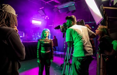 Falmouth University students in a purple lit film studio with camera